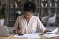 Focused African American millennial woman checking papers for payment Royalty Free Stock Photo