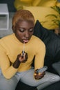 Focused african american woman applying lip gloss and looking Royalty Free Stock Photo