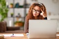 Focused african american female in headphones looking at laptop screen and thinking while working remotely or studying online from Royalty Free Stock Photo