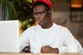 Concentration black hipster male in headphones, eyewear studying or working remotely on computer Royalty Free Stock Photo