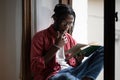 Focused African guy college student wearing eyeglasses learning foreign language by reading books Royalty Free Stock Photo