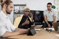 Focused african man speaks on the phone while his male colleagues listening speech of businessman Royalty Free Stock Photo