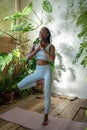 Black woman meditating in yoga tree pose stand on one leg with closed eyes at home garden. Wellness. Royalty Free Stock Photo