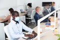 Focused afro american businessman in medical mask working in office