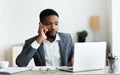 Focused afro businessman talking on cellphone and working on laptop Royalty Free Stock Photo