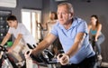 Aged man doing cardio workout on exercise bike in gym Royalty Free Stock Photo