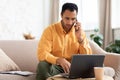 Focused Arab man working and talking on phone at home Royalty Free Stock Photo