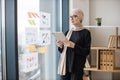 Manager with tablet standing near window with infographics