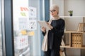 Manager with tablet standing near window with infographics