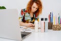 Focused artist woman painting plywood figures behind work desk with a brush Royalty Free Stock Photo