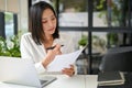 Focused Asian businesswoman reviewing business document or analyzing financial data report Royalty Free Stock Photo