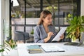 Focused Asian businesswoman reviewing marketing reports at her desk in the office Royalty Free Stock Photo