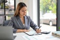 Focused Asian businesswoman reviewing sales data reports, working at her desk in the office Royalty Free Stock Photo