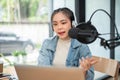 A focused Asian female radio host is speaking into a microphone, announcing news Royalty Free Stock Photo