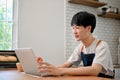 Focused Asian man in apron using laptop in his kitchen, joining online cooking class Royalty Free Stock Photo