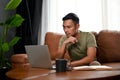 Focused Asian man looking at his laptop screen, planning a plan for his business project Royalty Free Stock Photo