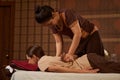 Licensed mature massotherapist giving female client Thai massage