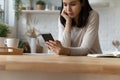 Focused Asian millennial girl using smartphone in home kitchen