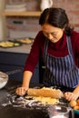 Focused asian woman baking rolling dough in kitchen