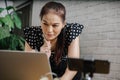 Focused Asian woman using laptop at home, looking at screen, chatting, reading or writing email Royalty Free Stock Photo