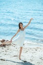 focused asian woman in white dress dancing on beach