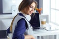 Focused attentive woman in headphones sits at desk with laptop, looks at screen, makes notes, learns foreign language in