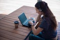 Focused attentive woman in headphones sits at desk with laptop, looks at screen, online study course, self-education.