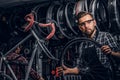 Focused attractive man in glasses is chainging wheel for bicycle at busy workshop Royalty Free Stock Photo