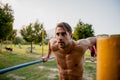 Focused attractive young male athlete working out arms using horizontal bars in sunny outdoor park Royalty Free Stock Photo