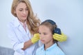 Focused audiologist preparing a young patient for an audiometry test
