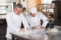 Focused bakers kneading dough at counter