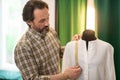 Focused bearded designer getting measurements of a finished white shirt