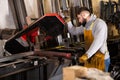 Metalworker cutting tubes on saw machine