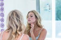 Focused beautiful young woman looking at herself in the bathroom mirror Royalty Free Stock Photo