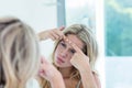 Focused beautiful young woman looking at herself in the bathroom mirror Royalty Free Stock Photo