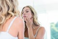 Focused beautiful young woman looking at herself in the bathroom mirror Royalty Free Stock Photo