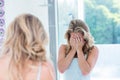 Focused beautiful young woman looking at herself in the bathroom mirror Royalty Free Stock Photo