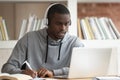 Focused biracial guy make notes watching educational webinar