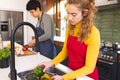 Focused of biracial lesbian couple chopping and washing vegetables in kitchen Royalty Free Stock Photo