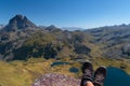 Focused boots of a hiker atop Ayous peak with unfocused views of Ayous mountain lake and the Pyrenees mountains with the Midi d`