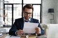 Focused business leader in formal suit and glasses reading letter