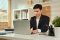 Focused businessman in black suit using laptop, searching information or working on project at workplace Royalty Free Stock Photo