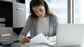 Focused businesswoman wearing headset writing notes, using laptop