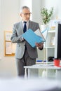 Focused busy old boss in clear glasses inspecting documents