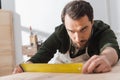 Focused carpenter looking at square tool