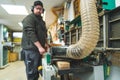 Focused carpenter standing next to sawdust extractor machine in protective gear. Blurred background. Royalty Free Stock Photo