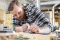 Focused carpenter work with plane on wood plank in workshop