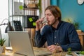 Businessman sitting at workplace desk drinking water while working with laptop in home office Royalty Free Stock Photo