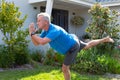 Focused caucasian senior man practicing yoga in garden