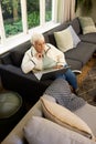 Focused caucasian senior woman using laptop in sunny living room